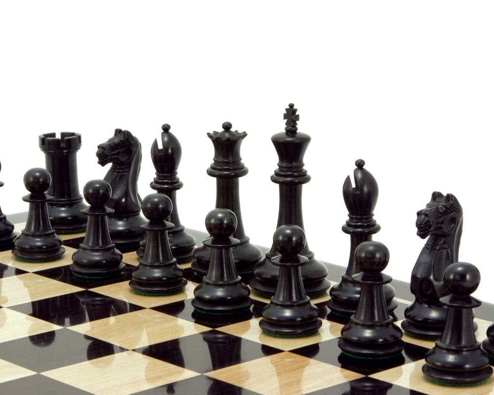 Handcrafted ebonised boxwood chess pieces on a chessboard, featuring intricately detailed black chessmen with a 3.75 inch king.