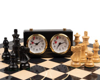 The French Knight Luxury Black Chess Set with Chess Clock on a black and white chessboard